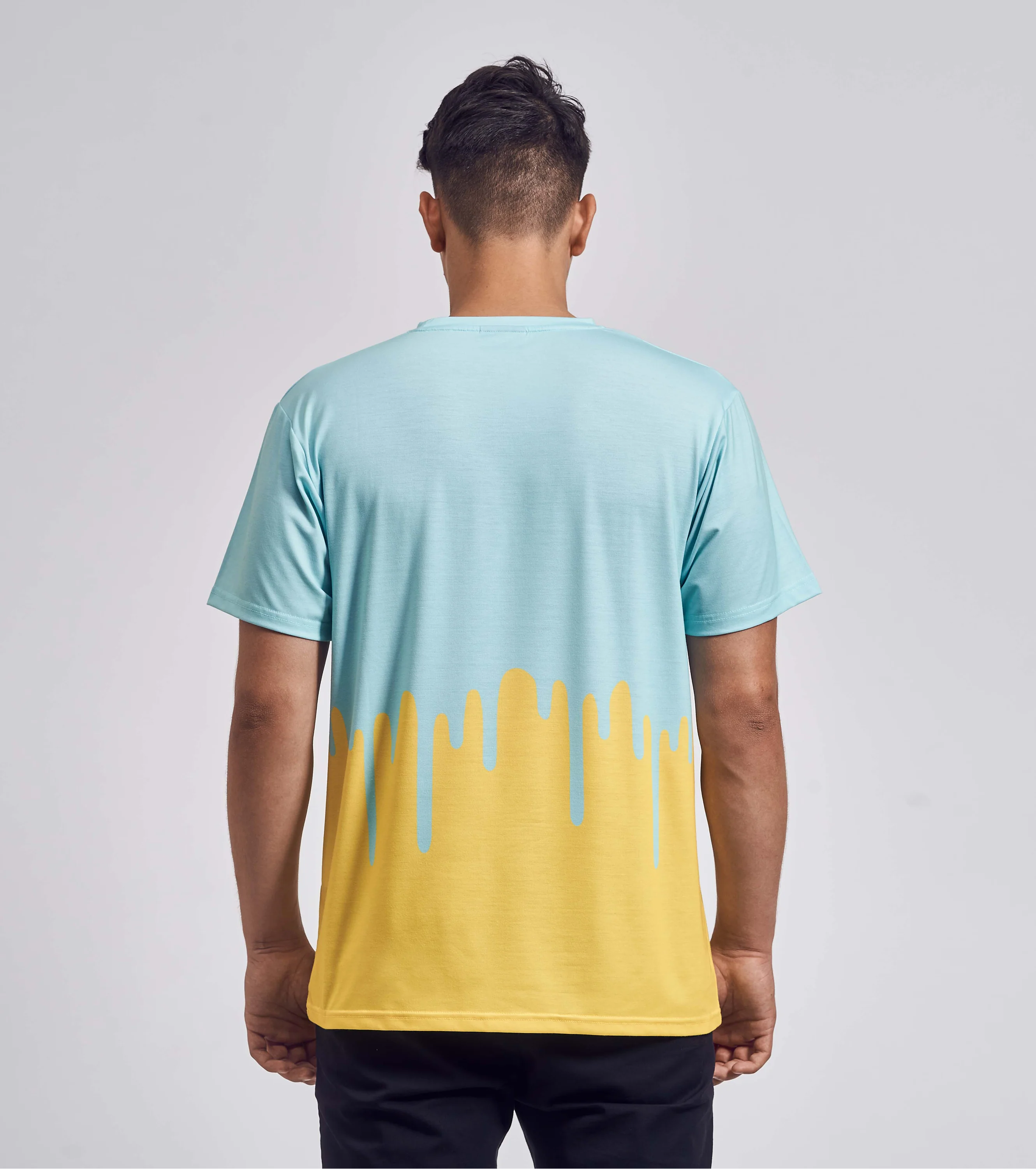 Rückansicht eines T-Shirts mit Drip-Design in Gelb und Hellblau, getragen von einem jungen Mann mit dunklen Haaren