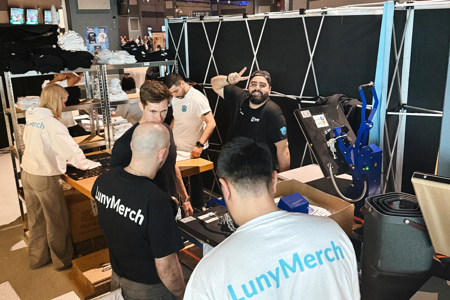 Live-Produktion am Creator Day von LewinRay: DTF-Druckmaschine und Regale mit fertig bedruckten T-Shirts am LunyMerch-Stand