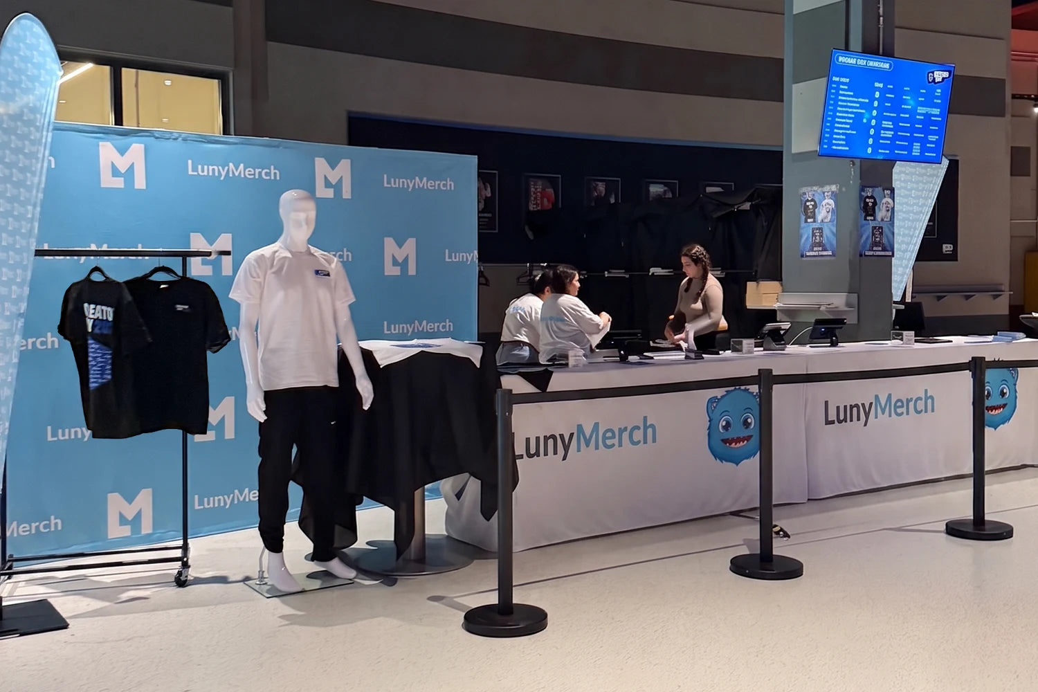 LunyMerch-Verkaufsstand am Creator Day mit Hussen, Verkaufspostern, Personal, Schaufensterpuppe und Creator-Day-T-Shirt