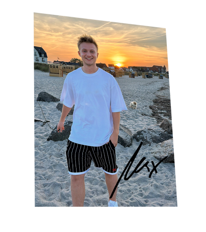Autogrammkarte mit Max am Strand bei Sonnenuntergang – lässiges Sommeroutfit mit weißem Oversize-Shirt und gestreifter Shorts, signiert mit schwarzem Marker.

