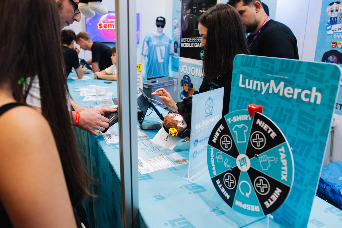 Glücksrad und LunyMerch Aufsteller an der Kasse des Messestands auf der gamescom 2026