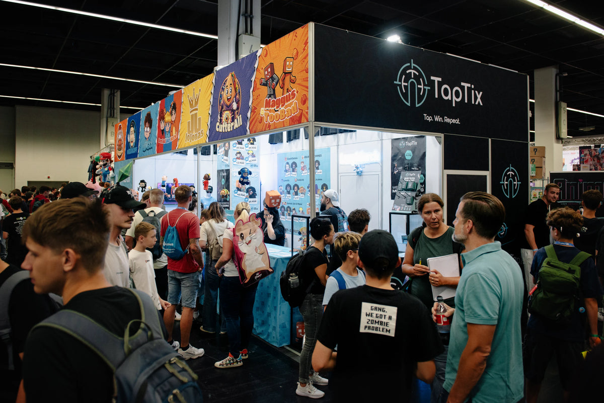 Eckansicht des LunyMerch Stands mit TapTix Turm und Besuchermenge in Halle 5.2 auf der gamescom 2026